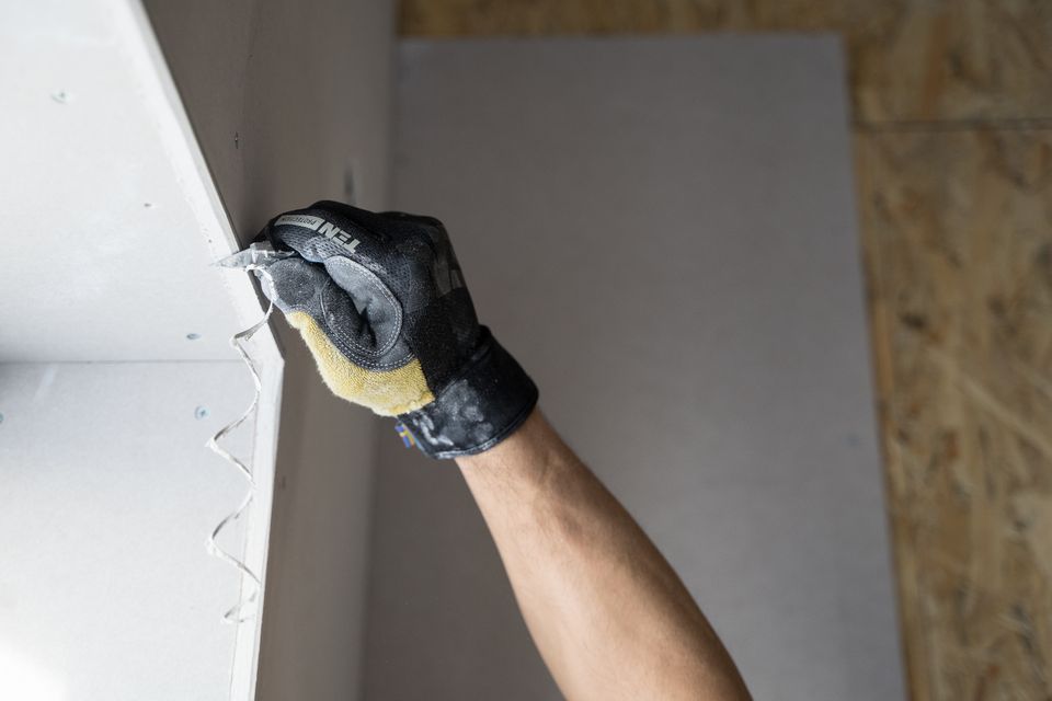 Worker in gloves removing damaged wall material